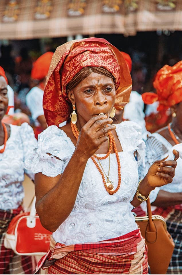 Woman blowing a whistle in traditional attire and coral beads