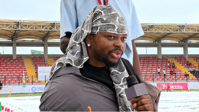 Fola David speaking into a microphone at the stadium