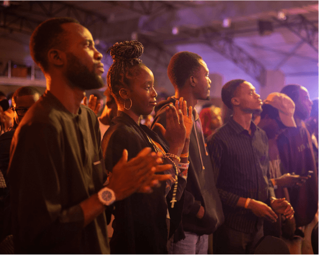 Young worshippers lined in prayer under stage lights