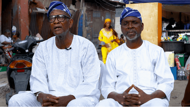 Two elders in traditional attire being interviewed