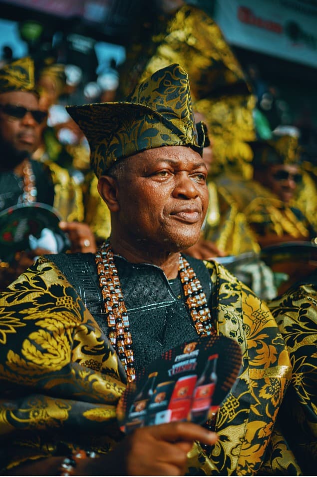 Elder in black and gold ceremonial attire with coral beads