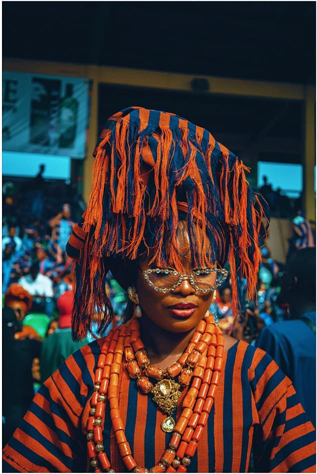 Woman in orange and navy aso oke with jewelled cat-eye glasses