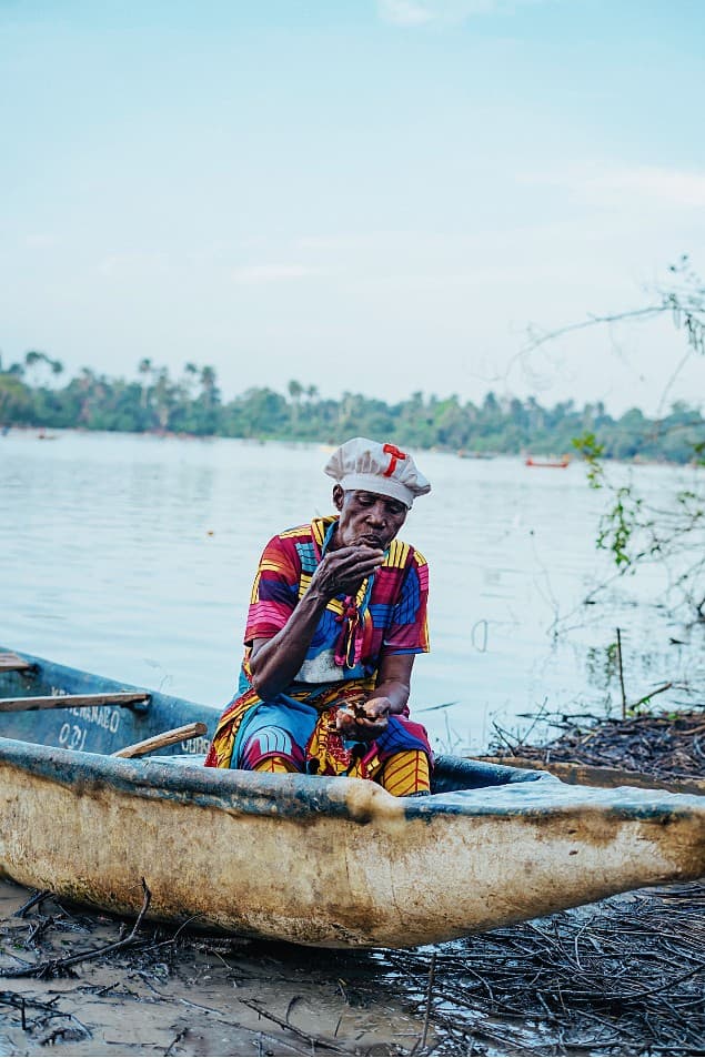 Elderly woman resting in a beached dugout canoe