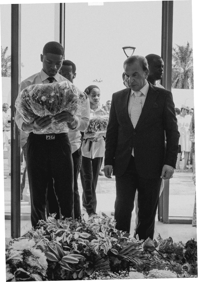 Black-and-white moment of mourners with floral tributes